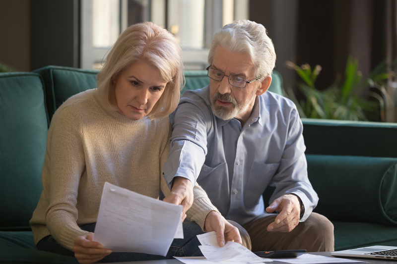 Two elderly homeowners reading a couple of tax forms