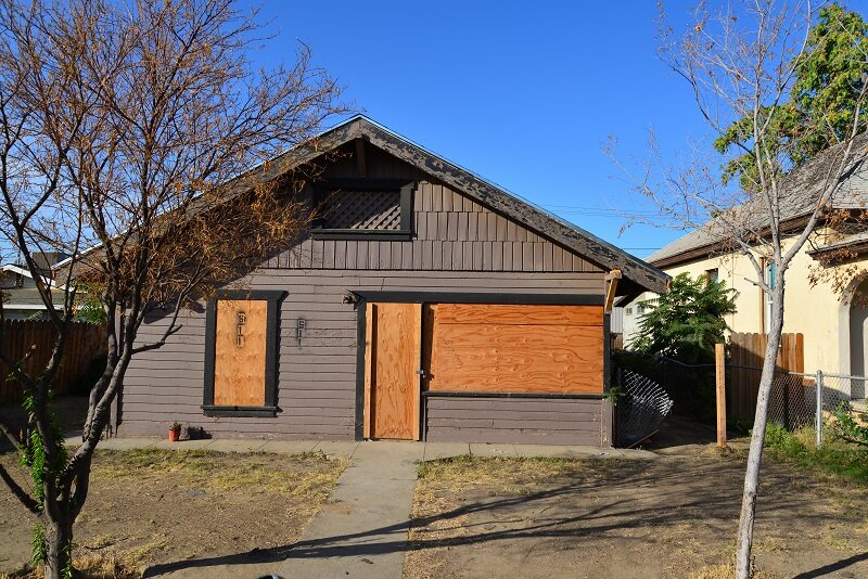 A boarded up house with plywood in its window frames. Boarding it up is often one of the first things that happens when a house is condemned